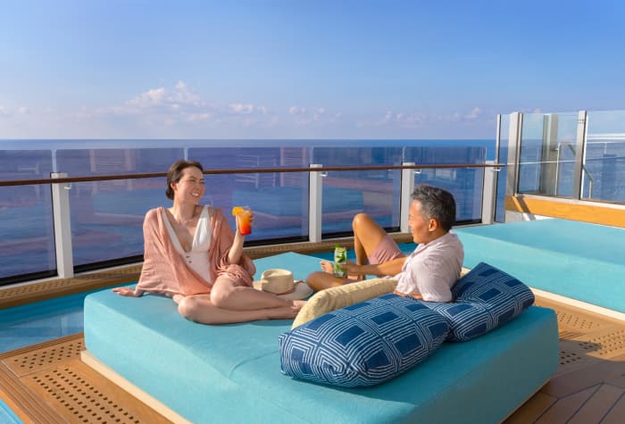 A couple relaxing onboard Norwegian Prima cruise ship at the infinity beach on lounger
